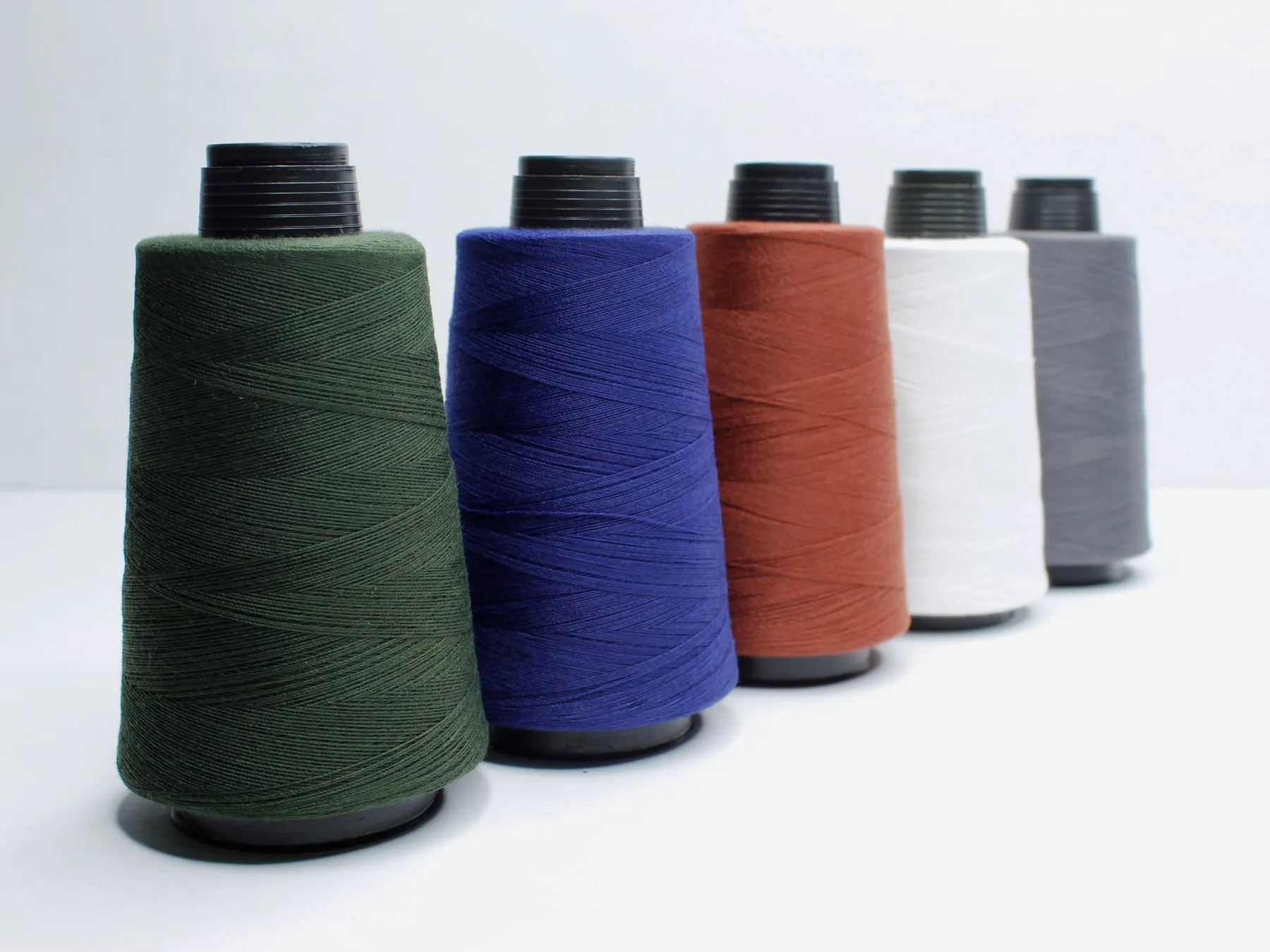 Conos del Art. 100 de hilo Terry en verde oscuro, azul, terracota, blanco y gris.