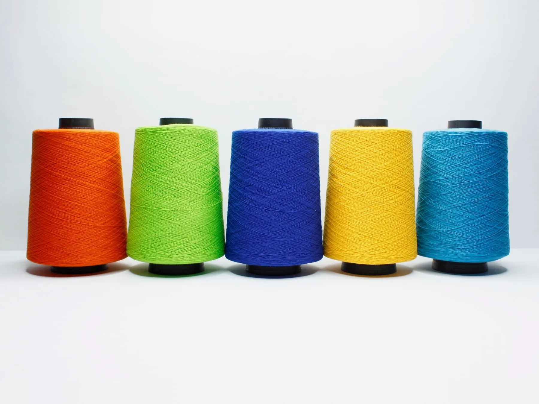 Conos industriales de hilo Terry en naranja, verde limón, azul, amarillo y turquesa.